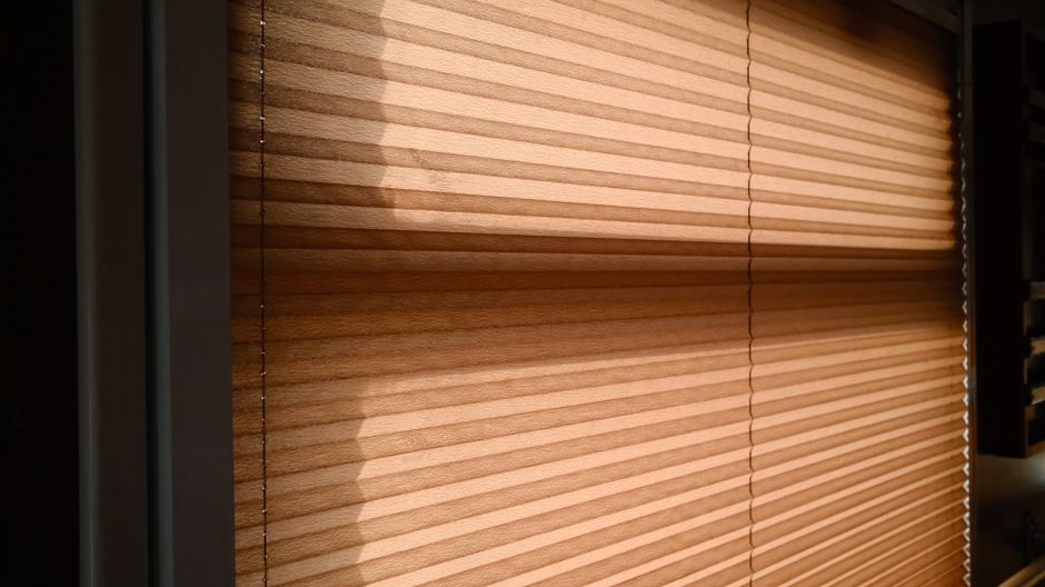 Speelse lichtvlekken door geperforeerde rolgordijnen in keuken.